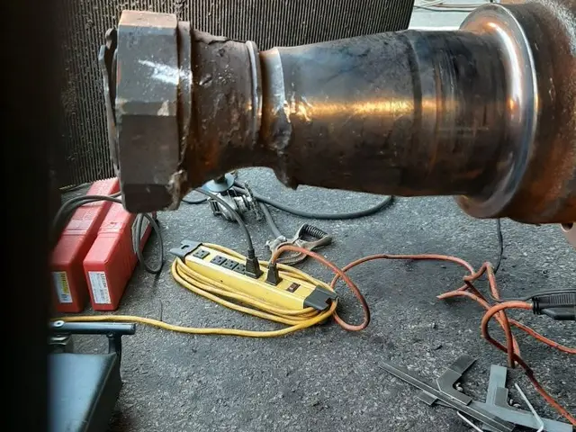 A large metal pipe sitting on the ground next to a yellow power strip.